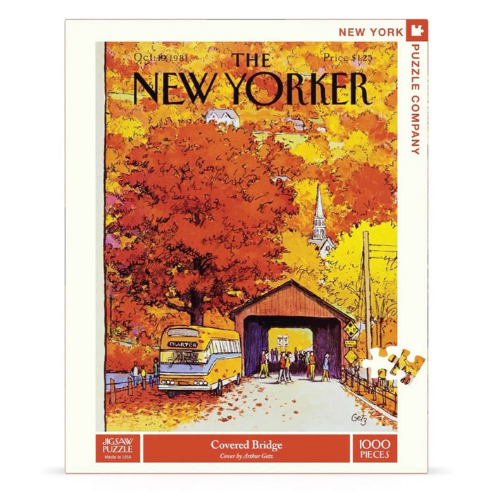 Front of box for a 1000 piece jigsaw puzzle of a New Yorker magazine cover with tourists from a yellow charter bus wandering around a small covered bridge surrounded by fall foliage and a church steeple rising above it on hill.