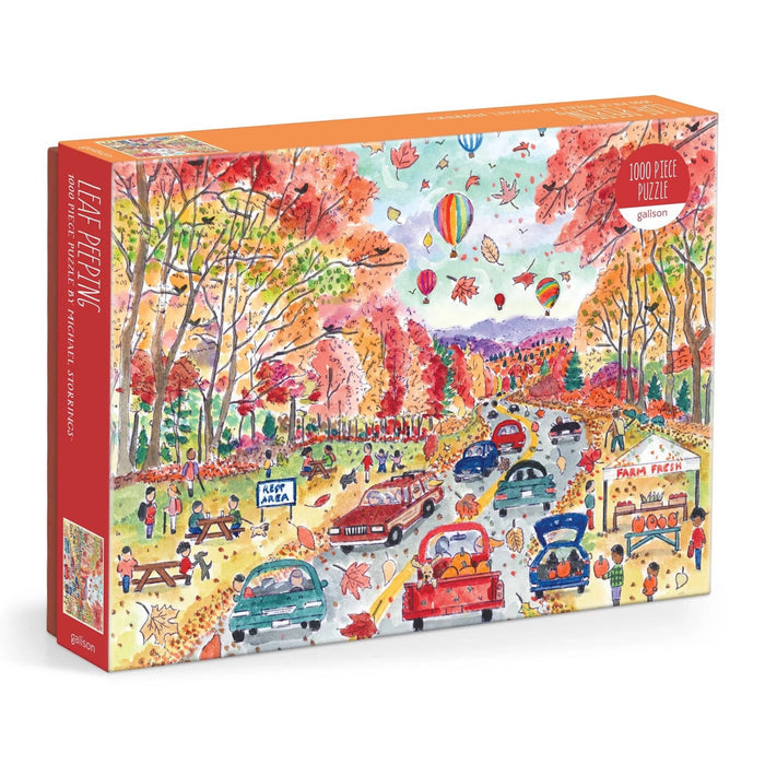 A 1000-piece jigsaw puzzle box titled 'Leaf-Peeping' by Galison featuring a colorful, busy autumn street scene with cars, people, hot air balloons, and fall foliage.