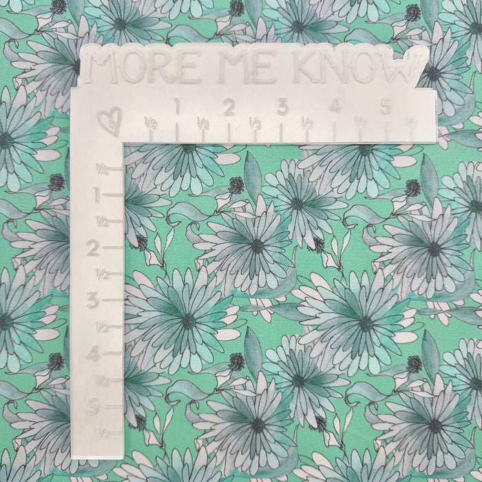 This printed WPCotton features daisy flowers in hues of mint. This photo shows a white L shaped ruler for scale.