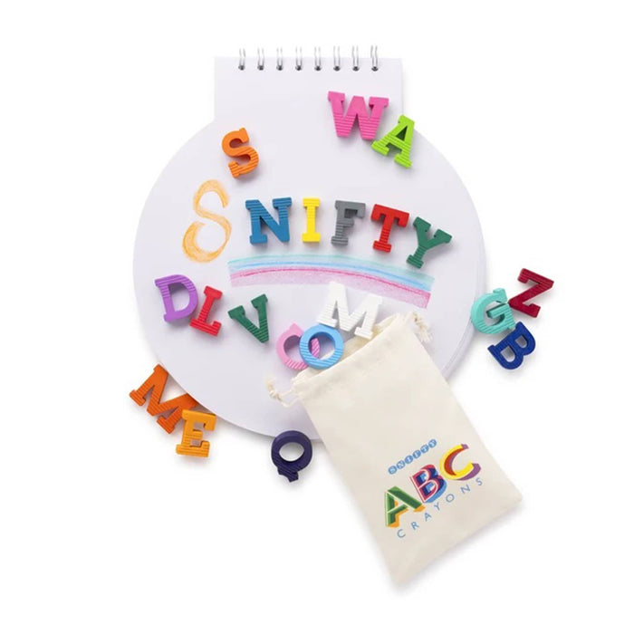 A set of colorful letter crayons, shown with a cream-colored drawstring pouch and a round white spiral-bound notebook on a clean white background.