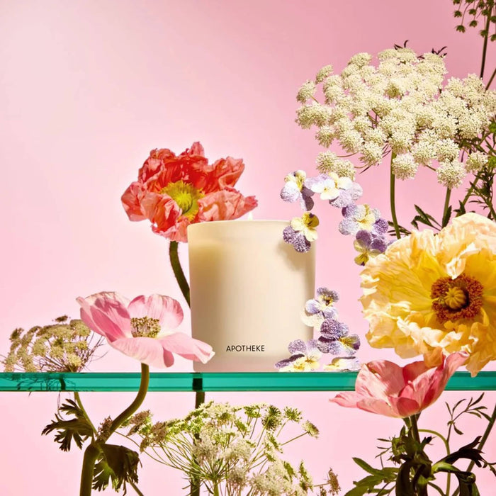 Candle with flowers on a pink background.