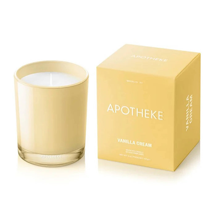 Apotheke Vanilla Cream scented candle in a soft yellow glass vessel and its matching box on a white background.