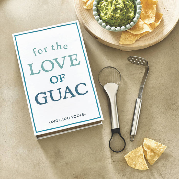 Avocado tools with book box that says 'For the Love of Guac', on a table with guacamole and tortilla chips.