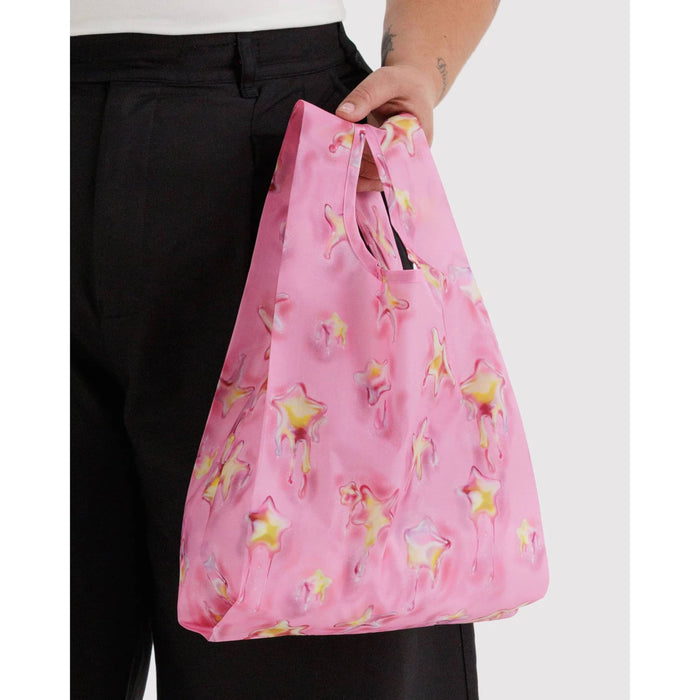 Person holding a pink reusable bag with dancing starfish patterns, on a white background.