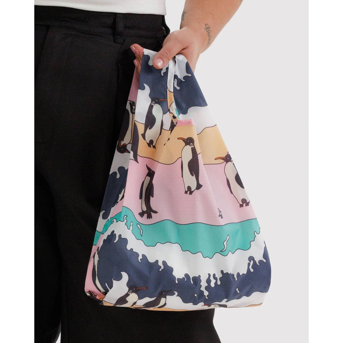 Person holding a colorful bag with penguin design.