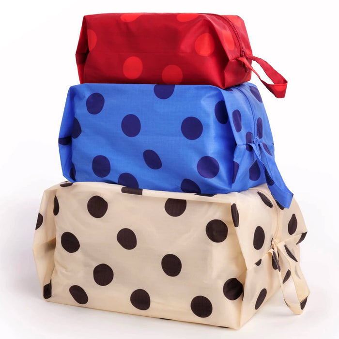 Three reusable zippered pouches stacked on top of each other, featuring a red one with red polka dots, a blue one with dark blue polka dots, and a cream one with black polka dots. The pouches are shown on a clean white background.