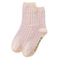 A pair of light beige crew socks with a repeating lilac houndstooth pattern and olive green 'BAGGU' branding printed on the sole, shown against a plain white background.