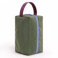 A caper green insulated lunch bag with a dark plum top handle, and a light blue zipper, on a white background.