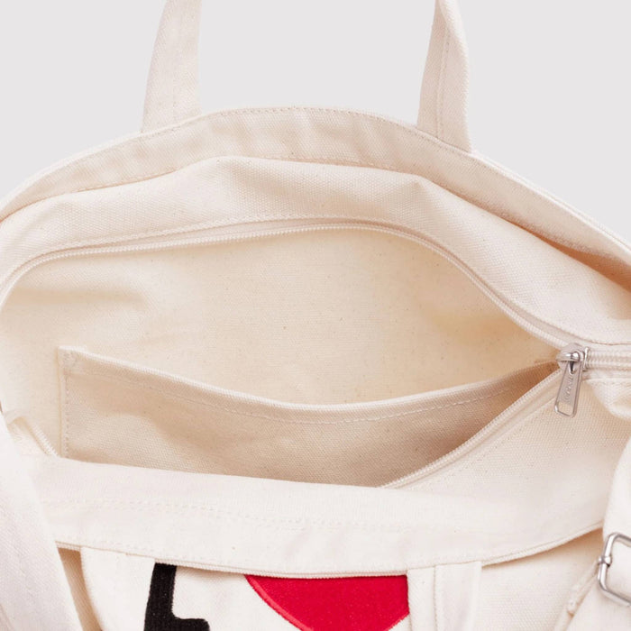 Close-up of a white canvas tote with a zipper on a white background.