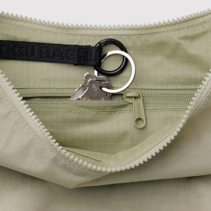Baggu Celadon medium ripstop nylon crescent bag, detail of interior pocket, on a white background.
