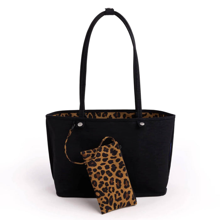 A black canvas tote bag with a leopard print interior lining and a matching leopard print wristlet pouch, shown on a plain white background.