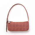 A small rectangular houndstooth shoulder bag in shades of red and tan with matching strap and a silver zipper pull with a circular logo charm, set against a plain white background.