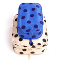 2 recycled nylon zippered packing cubes, large bag is cream with black polka dots, smaller bag is blue with navy polka dots, stacked on a white background.