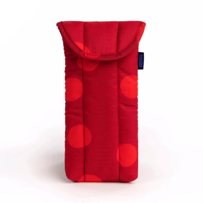 A red quilted fabric glasses pouch with a large polka dot pattern in shades of red, featuring a fold-over flap and a small dark blue brand tag on the side.
