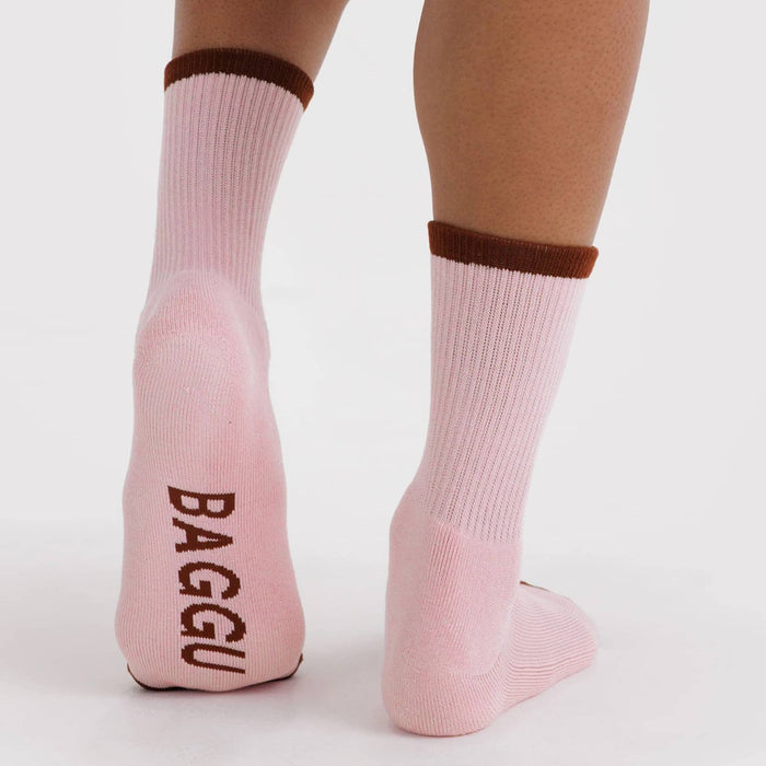 Pink socks with burgundy accents and 'BAGGU' branding on the sole, on a white background.