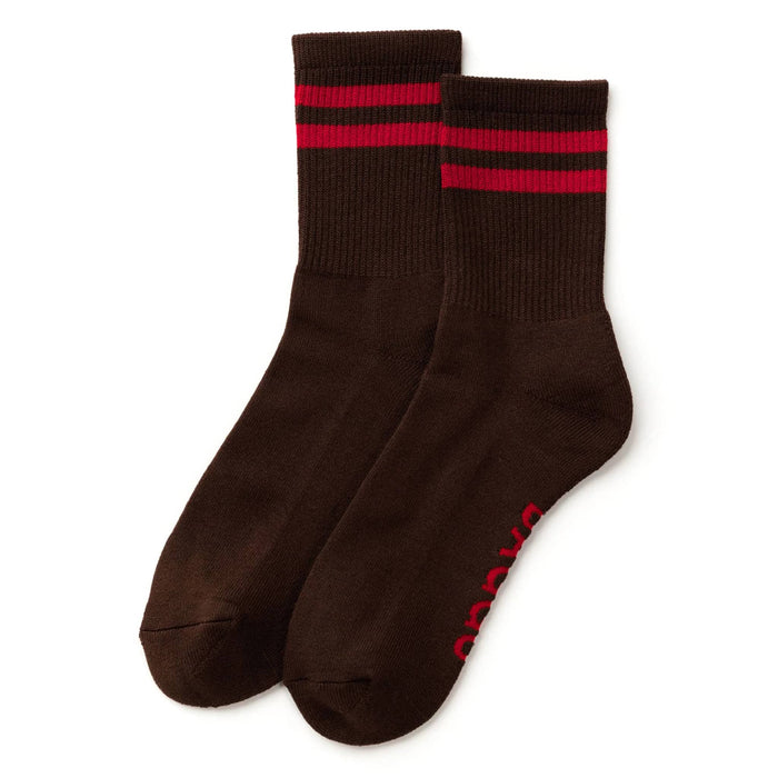 A pair of dark brown crew socks with two red stripes near the ribbed cuffs and red branding printed on the sole, displayed against a plain white background.
