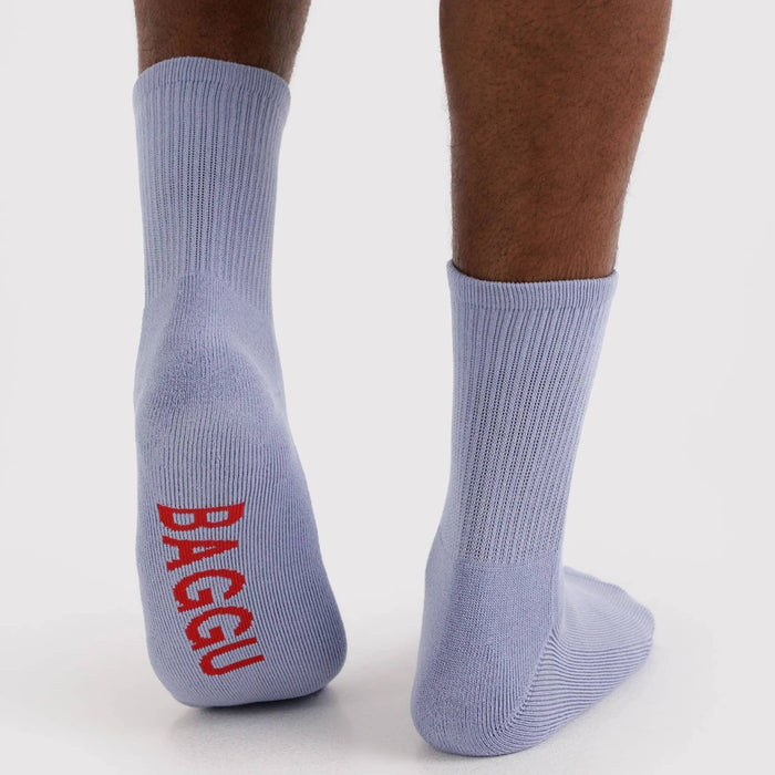 Light blue socks with red 'BAGGU' logo worn by a person on a white background.