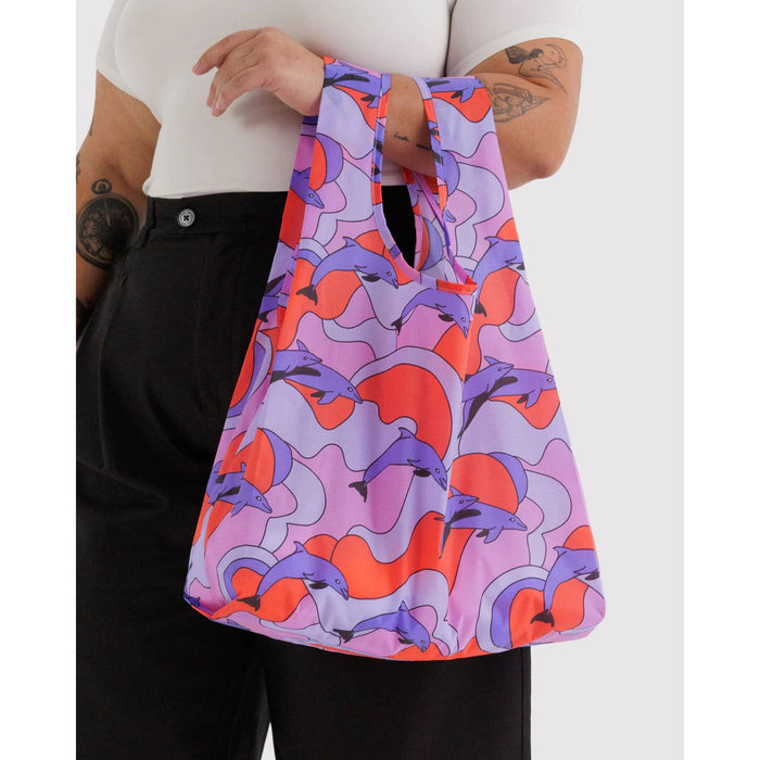 Person holding a colorful bag with abstract dolphin design on a white background.