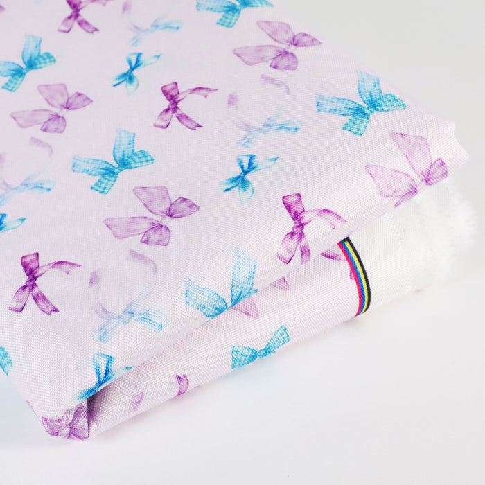 This printed WPC-Lite consists of a variety of styled bows in blue, turquoise, purple, and magenta. This photo shows the fabric folded.