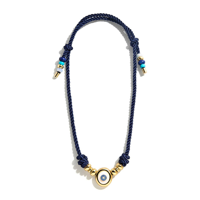 Necklace with navy blue cord and gold beads with an evil eye charm, full length view, on a white background.