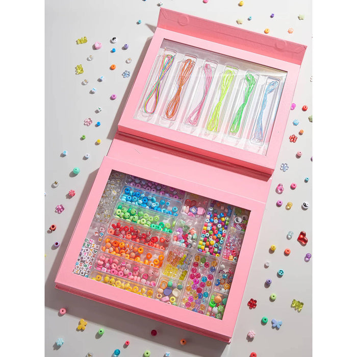 Pink jewelry-making kit with beads and strings on a gray background.