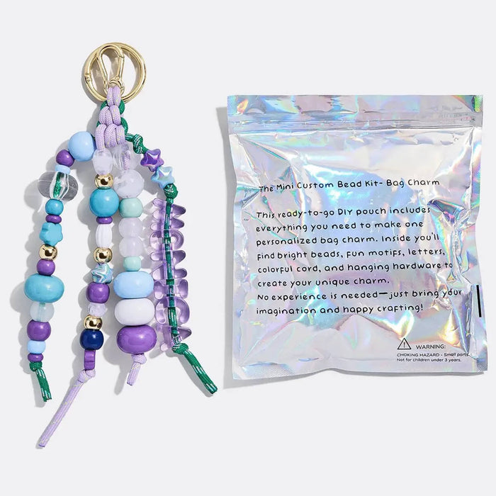 Completed colorful beaded bag charm keychain project with back of pouch packaging on a white background.