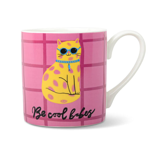 A white ceramic mug featuring a pink grid pattern with a yellow spotted cat wearing blue sunglasses and the text 'Be cool babes' in black script. Handle is on the right, on a white background.