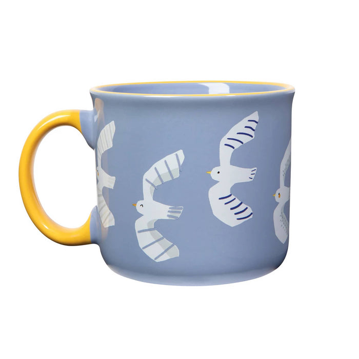 Blue mug with white seagull illustrations and a yellow handle, on the left, on a white background.