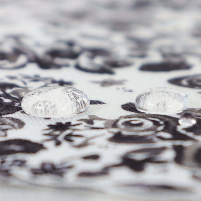 This printed WPC-Lite is of a variety of black flowers on a white background. This photo shows 2 water drops on the fabric.