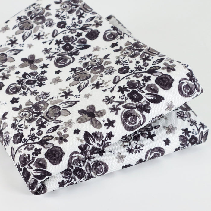 This printed WPC-Lite is of a variety of black flowers on a white background. This photo shows the fabric folded.