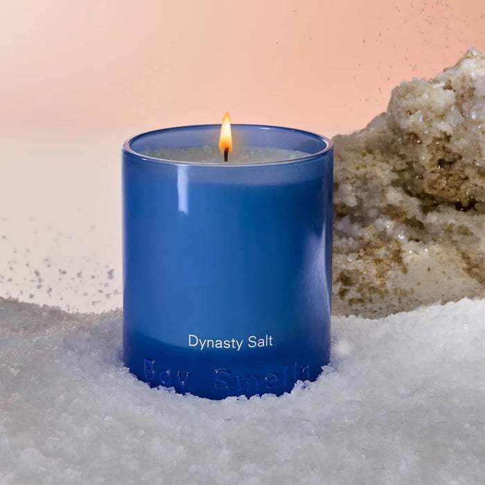 Boy Smells Dynasty Salt scented 9 ounce Essentials candle in blue glass vessel, front view, with salt around.