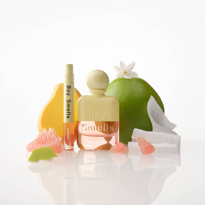 Full size and travel spray of Boy Smells Solar Drip perfume with fruit and flowers, on a white background.