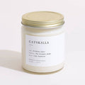 Brooklyn Candle Studio Catskills scented candle in clear jar with gold lid, front view.