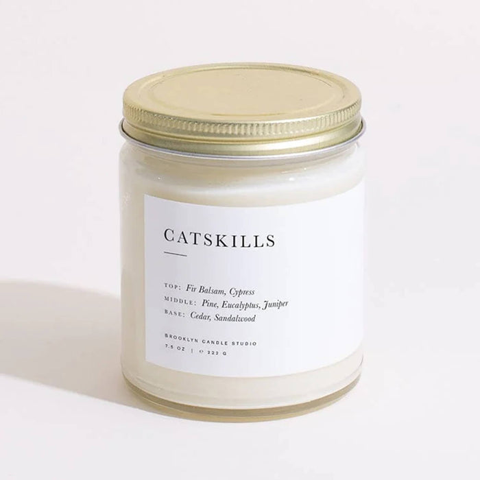 Brooklyn Candle Studio Catskills scented candle in clear jar with gold lid, front view.