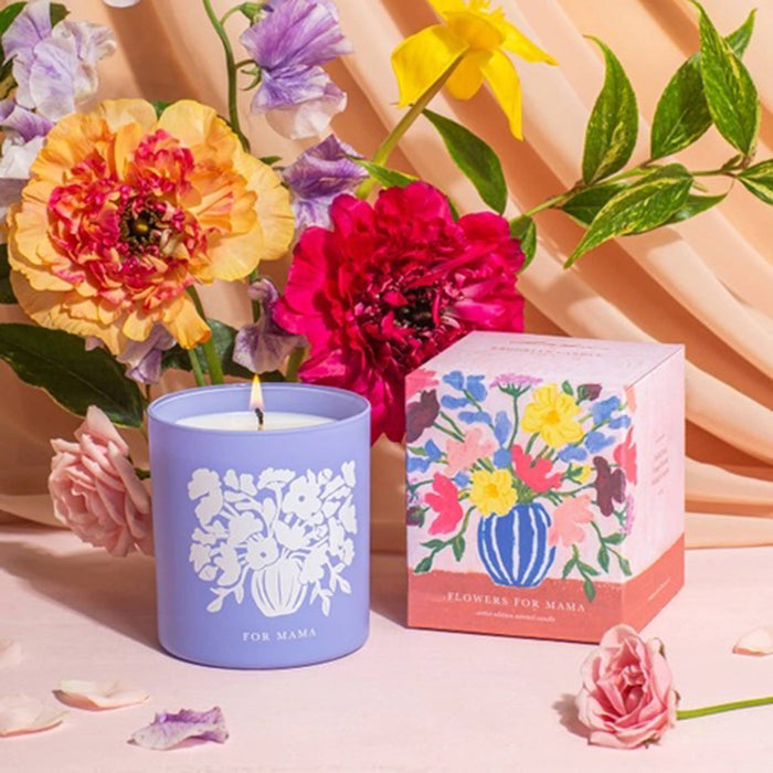 Brooklyn Candle Studio Flowers for Mama scented candle in a periwinkle vessel next to a floral print gift box, with flowers and a pink and peach background.