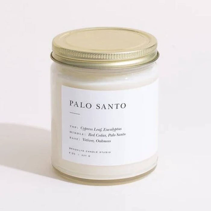Brooklyn Candle Studio Palo Santo scented candle in clear jar with gold lid, front view.