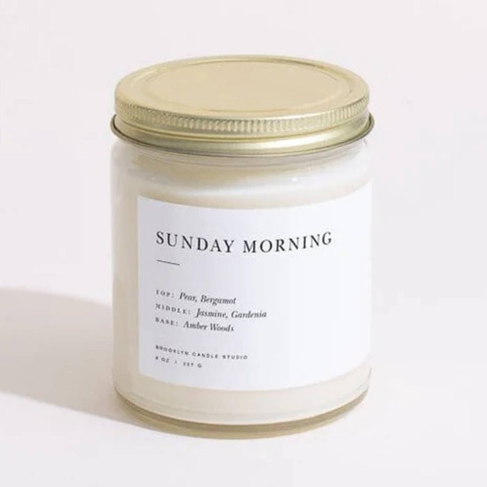 Brooklyn Candle Studio Sunday Morning scented candle in clear jar with gold lid, front view.