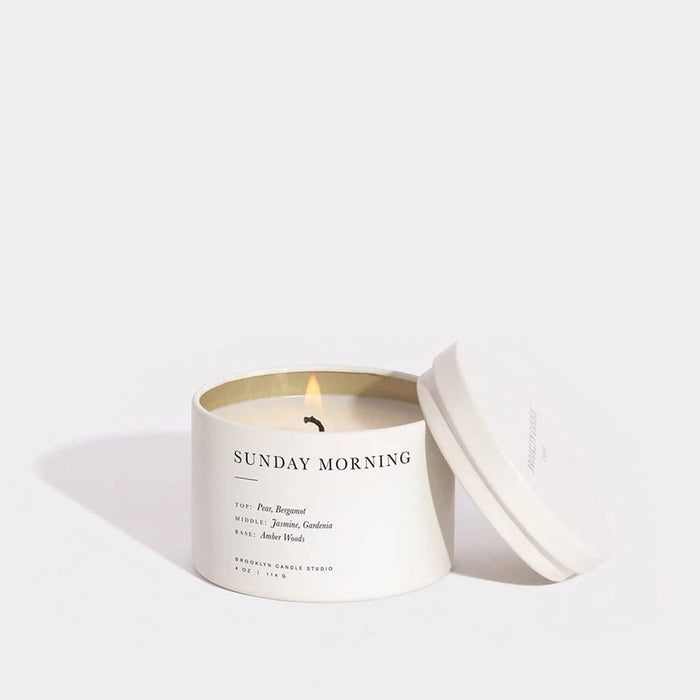 Brooklyn Candle Studio Sunday Morning scented soy wax travel candle in white tin, lid off and lit.