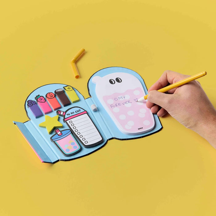 Hand holding a yellow pen over an open sticky notes set in different shapes and sizes, on a yellow background