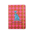 A softcover notebook with a pink and red diamond pattern, featuring a blue Dalmatian illustration and the text 'BUILDING MY EMPIRE' on the front cover, secured with a lime green elastic band.