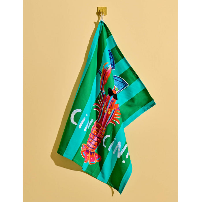 A green and turquoise striped cotton tea towel featuring a colorful lobster wearing sunglasses and holding blue martini glasses, with the text 'Cin Cin!' in white, hanging against a yellow background.