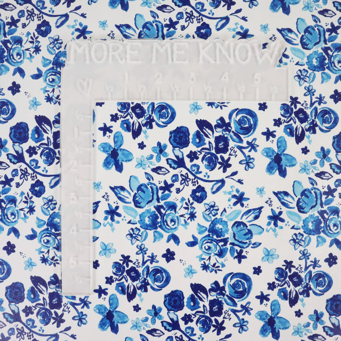 This floral print is in shades of blue with a white background. This photo shows an L-shaped ruler for size.
