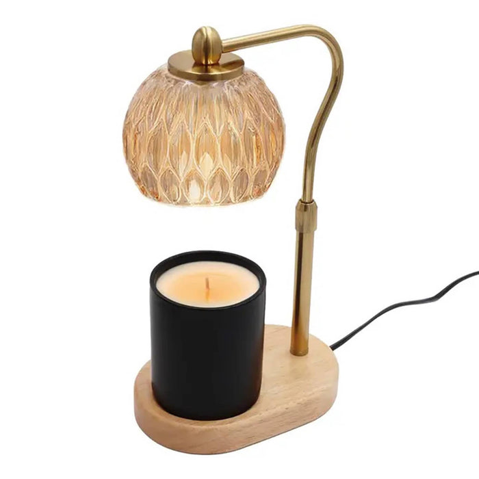 Candle warmer table lamp with crystal amber glass shade, adjustable gold stem, and wooden base, side angle view with a candle in a black vessel, on a white background.