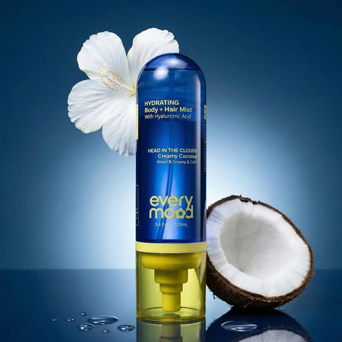 Everymood Dreamcatcher scented hydrating body and hair mist in blue and yellow bottle packaging with a coconut and white orchid, against a blue background.