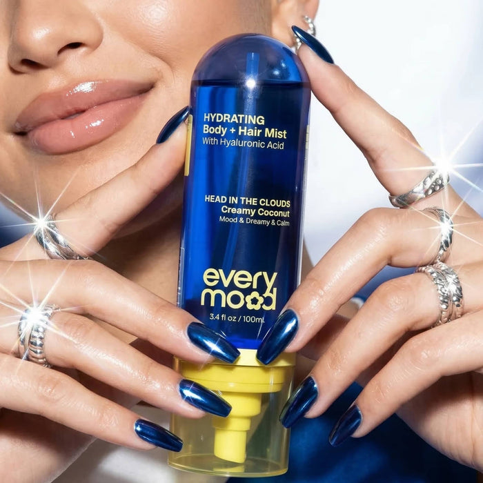 Person holding a bottle of Everymood Dreamcatcher scented hydrating body and hair mist against a white background.