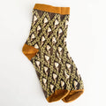 A single ankle sock with a brown and beige harlequin diamond pattern, featuring solid mustard yellow trim at the cuff, heel, and toe, laid flat on a white background.