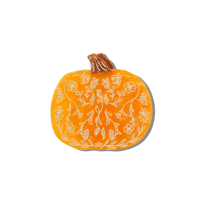 An orange pumpkin-shaped hair claw clip etched botanical design, front view with a soft gray shadow, centered on a plain white background.