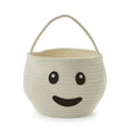 An off-white woven basket with a smiling face design on the front and a matching top handle, set against a plain white background.