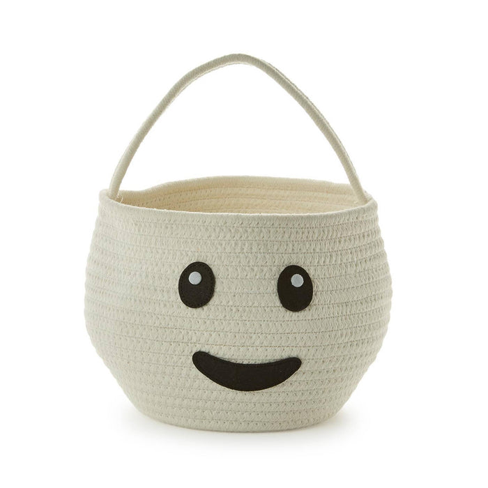 An off-white woven basket with a smiling face design on the front and a matching top handle, set against a plain white background.