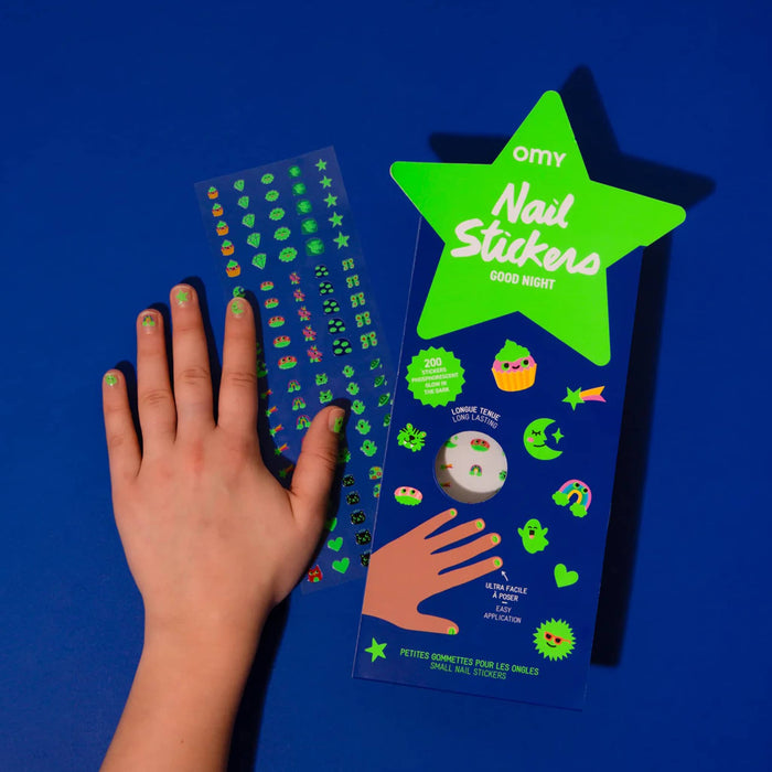 Glow in the dark nail sticker packaging with a hand showing nail designs on a blue background.